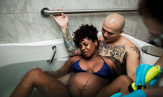 Woman in labor in bathtub with man supporting her