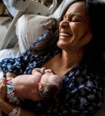 happy woman who just gave birth holding her new baby